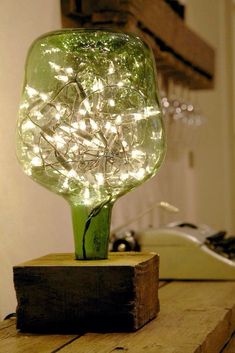 a green vase with lights in it sitting on top of a wooden table