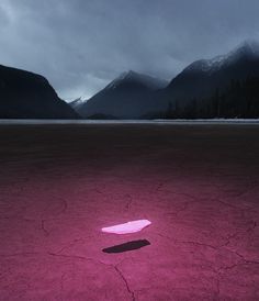 a pink object is in the middle of an empty field with mountains in the background