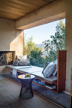 a living room with a couch, table and fire place in front of a large window