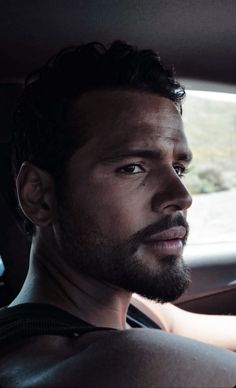 a man sitting in the passenger seat of a car looking off into the distance with his eyes open