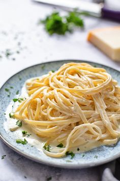 a plate full of pasta with parsley on the side next to cheese and bread