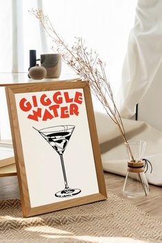 a sign that says giggle water next to a glass with a drink in it on a table