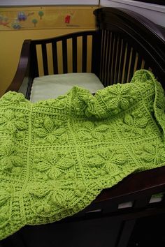 a crocheted blanket on top of a wooden crib