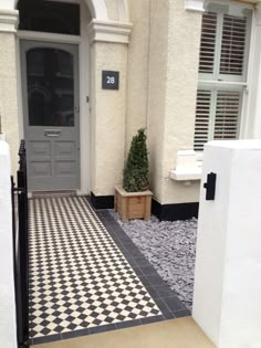 a black and white checkered tile floor in front of a house with a door