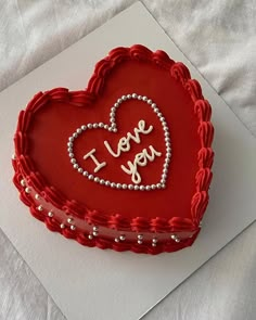 a red heart shaped cake with i love you written on it