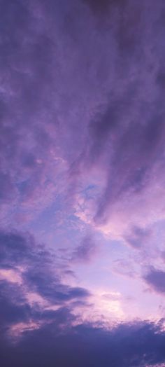 an airplane is flying in the sky at sunset or dawn with purple clouds above it