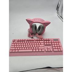 a pink computer keyboard with headphones on it