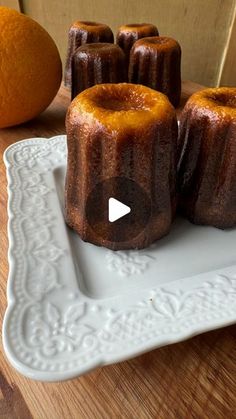 there are several cakes on the plate with an orange in the background