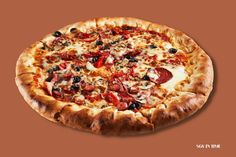 a pizza with pepperoni, olives and other toppings on a brown background