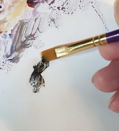 a person is holding a brush and drawing with watercolors