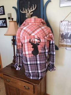 an image of a deer shirt on top of a wooden table with a lamp next to it