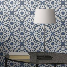 a lamp on a table in front of a blue and white wallpaper with an intricate design