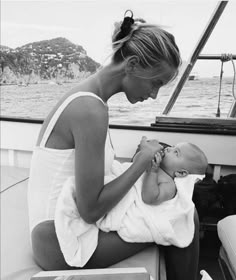 a woman holding a baby in her lap while sitting on a boat