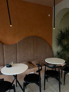 a table and chairs in a room with an orange wall behind the bench, next to a potted plant