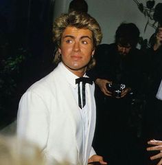 a man in a white suit and bow tie