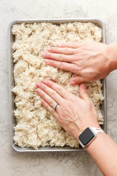 two hands touching each other over rice in a pan on a table with an apple watch