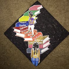 a graduation cap decorated with books and an image of a woman standing on top of it