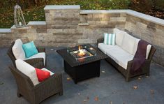 an outdoor fire pit surrounded by wicker furniture