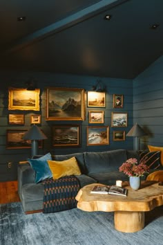 a living room with blue walls and pictures on the wall above the couch, along with a coffee table