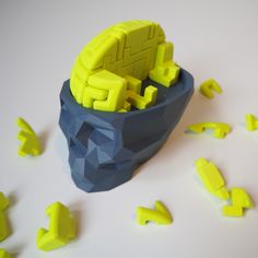 an object that looks like a skull with yellow pieces around it on a white surface