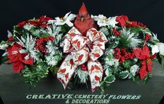 a red cardinal sitting on top of a green box filled with flowers and greenery