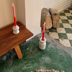 two candles are placed in small vases on a table