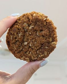 a person holding up a cookie in their hand with nuts on the top and crumbs on the outside