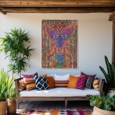 a couch sitting on top of a wooden floor next to potted plants and a painting