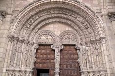 an old building with two wooden doors and ornate carvings on the front entrance to it