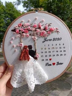 someone is holding up a cross stitch wedding decoration