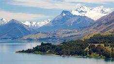 the mountains are covered in snow and green trees, near a body of water with a small island