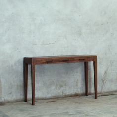 a wooden table sitting against a white wall