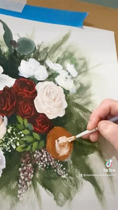 someone is painting flowers on a piece of paper