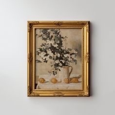 a painting hanging on the wall next to a vase with flowers and fruit in it