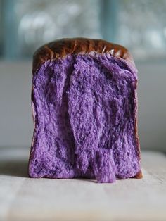 a close up of a piece of bread with purple frosting on the top and bottom