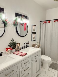 a white bathroom decorated for christmas with red bows on the shower curtain and wreaths