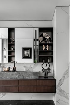 a modern bathroom with marble counter tops and black cabinetry, along with white walls