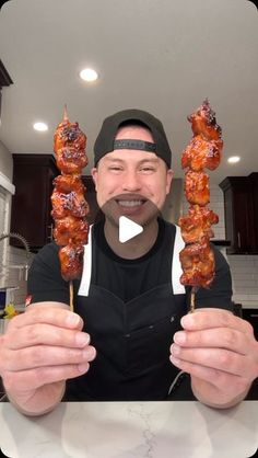 a man holding up two skewers of meat