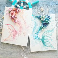 two cards with flowers and fish on them sitting next to each other in front of some beads