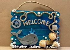 a welcome sign with sea shells and seashells hanging from it's side