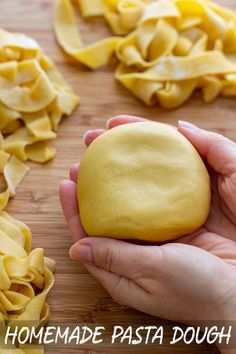 a person holding a doughnut in front of some uncooked pasta on a cutting board