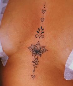 a woman's back with a tattoo design on her left side and hearts in the middle