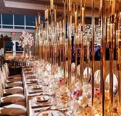 a long table is set up with gold and white plates, silverware, and flowers