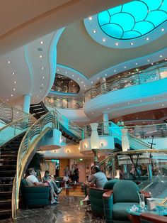 people are sitting at tables in a large room with stairs and circular lights on the ceiling