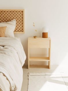 a bedroom with a bed, night stand and side table in the corner next to it