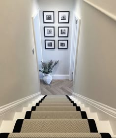 the stairs are lined with black and white chevron rugs, along with pictures on the wall