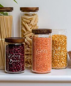 three glass jars filled with different types of pasta and other items on top of a shelf