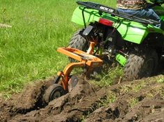 a man riding on the back of an orange four - wheeler through mud and grass