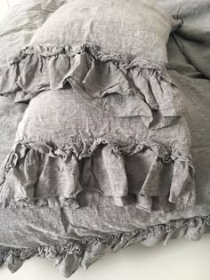 an unmade bed with ruffled linens and pillows on it's sides