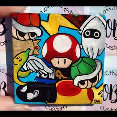 someone is holding up a small painting with mario and luigi on it's face